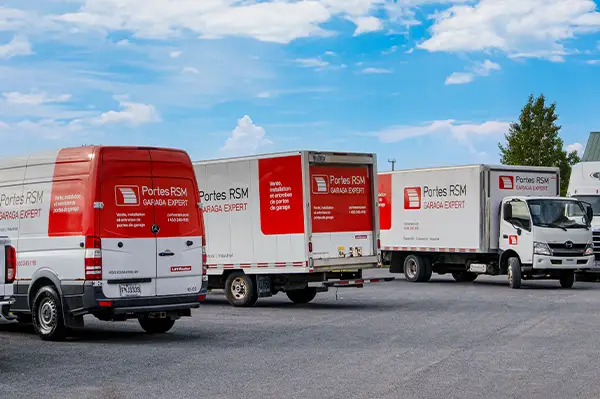 3 camions de service RSM portes de garage dans une cour commerciale